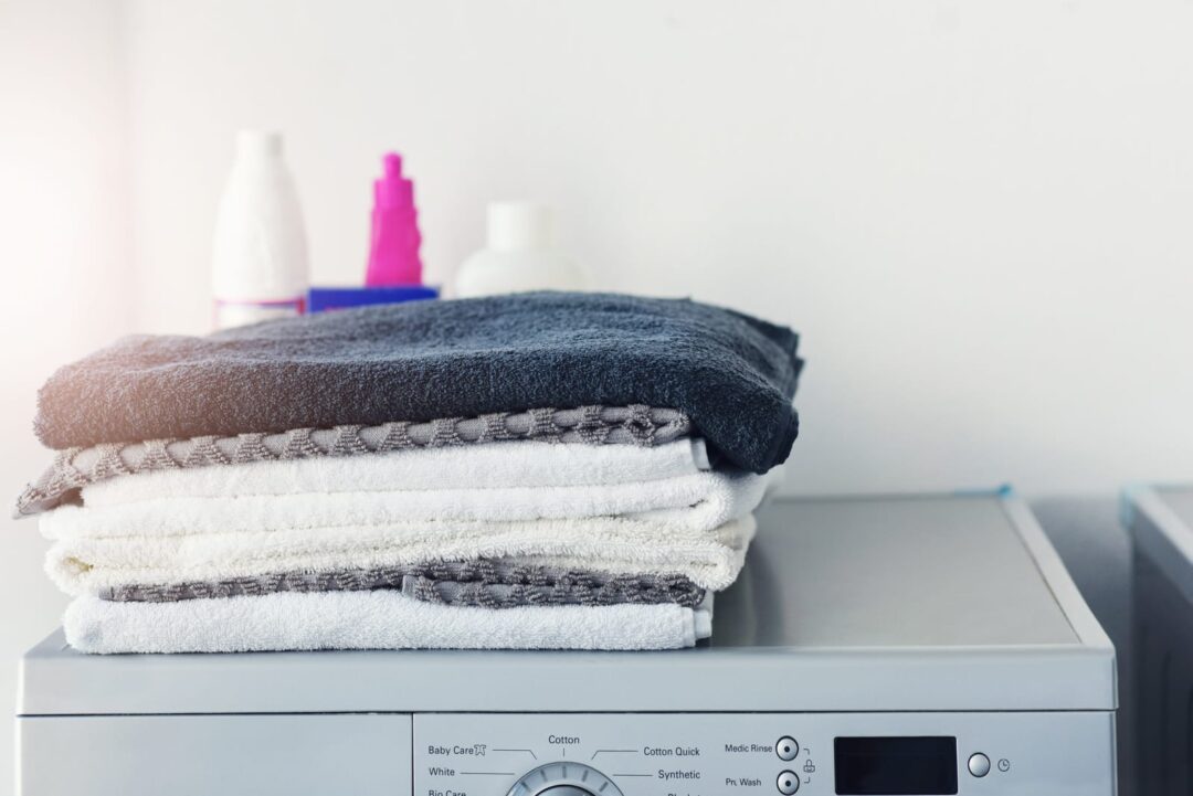 51796602 its laundry day a pile of linen folded on top of a washing machine at home