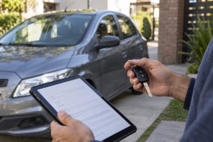 Persona revisando documentación junto a un auto y sosteniendo sus llaves