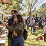 Familias disfrutando de puestos gastronómicos y música al aire libre en una fiesta rural