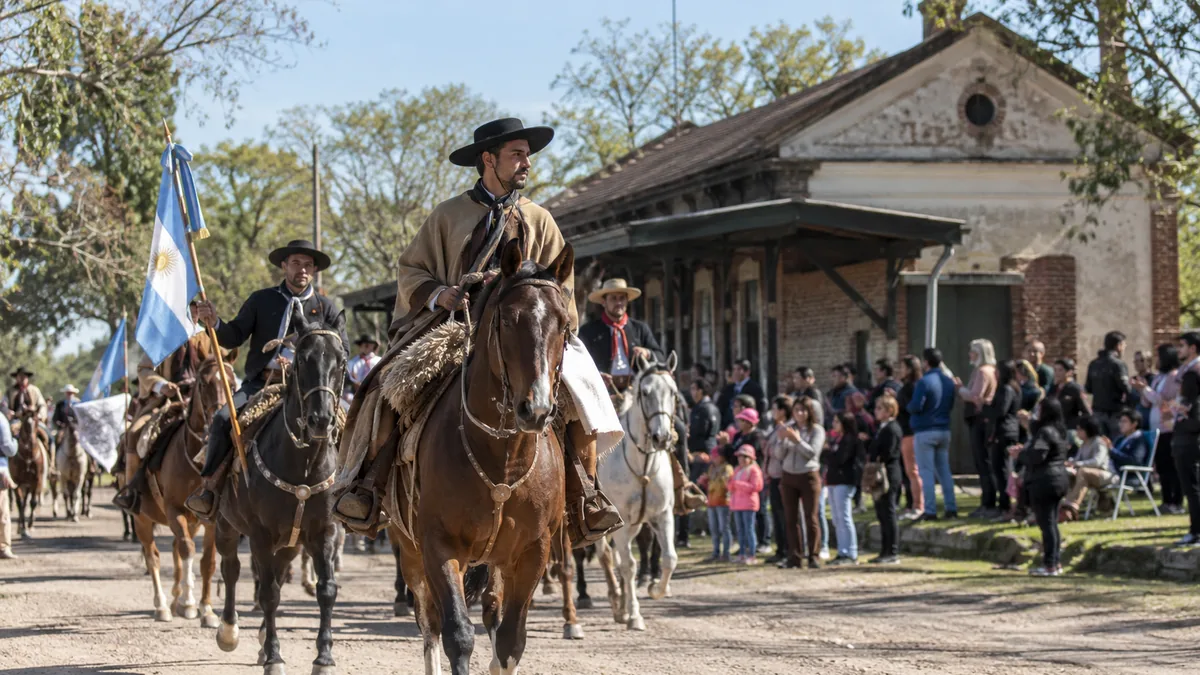 Una fiesta de pueblo que debió postergarse vuelve este fin de semana con fogón, caballos y entrada gratis 2 Jinetes y familias participando de un desfile criollo frente a una antigua estación ferroviaria