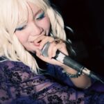 Cantante pop rubia se presenta sobre un escenario con un micrófono