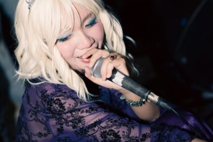 Cantante pop rubia se presenta sobre un escenario con un micrófono