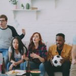 Grupo de amigos mirando un partido de fútbol por televisión