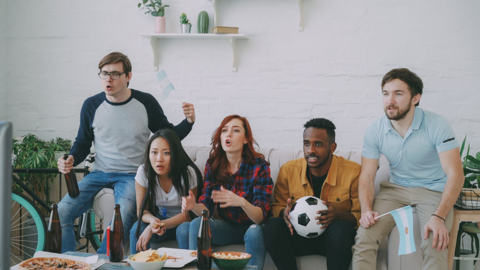 Grupo de amigos mirando un partido de fútbol por televisión