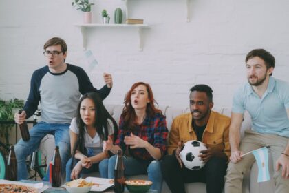 Grupo de amigos mirando un partido de fútbol por televisión