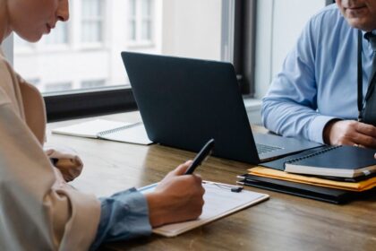 Personas revisan y firman documentos durante una reunión laboral