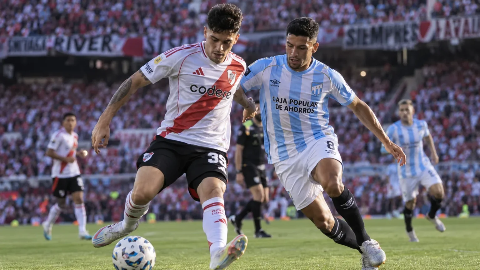 Un futbolista de river disputa la pelota con un jugador de atlético tucumán en un partido de la liga profesional