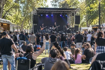 Banda tocando en un escenario al aire libre ante familias y público en un parque bonaerense