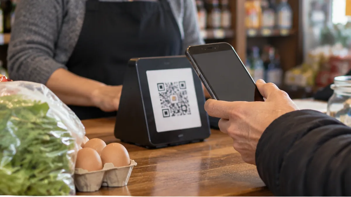 Cliente acercando un celular al código qr de un comercio con mercadería sobre el mostrador