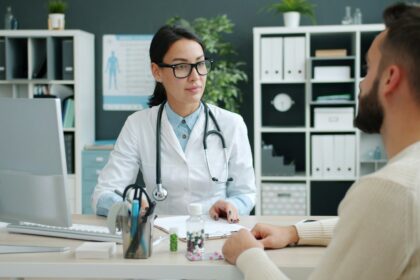 Médica conversa con un paciente joven en un consultorio