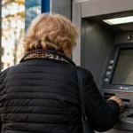 Adulto mayor frente a un cajero automático en una ciudad argentina