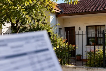 Fachada de vivienda familiar bonaerense y comprobante de impuesto desenfocado