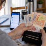 Mujer contando billetes argentinos en la mesa de su casa