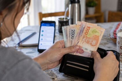 Mujer contando billetes argentinos en la mesa de su casa