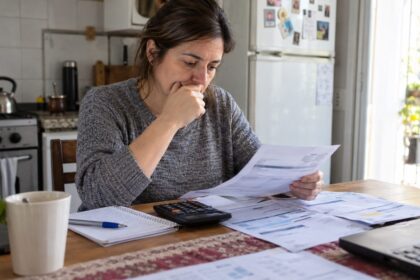Mujer revisando boletas y cuentas del hogar en la mesa de su casa